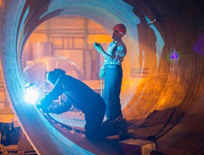 Two welders work in a pipe for an oil pipeline.